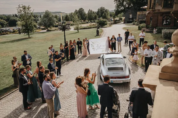 Brautpaar wird zum Hochzeitsauto geführt